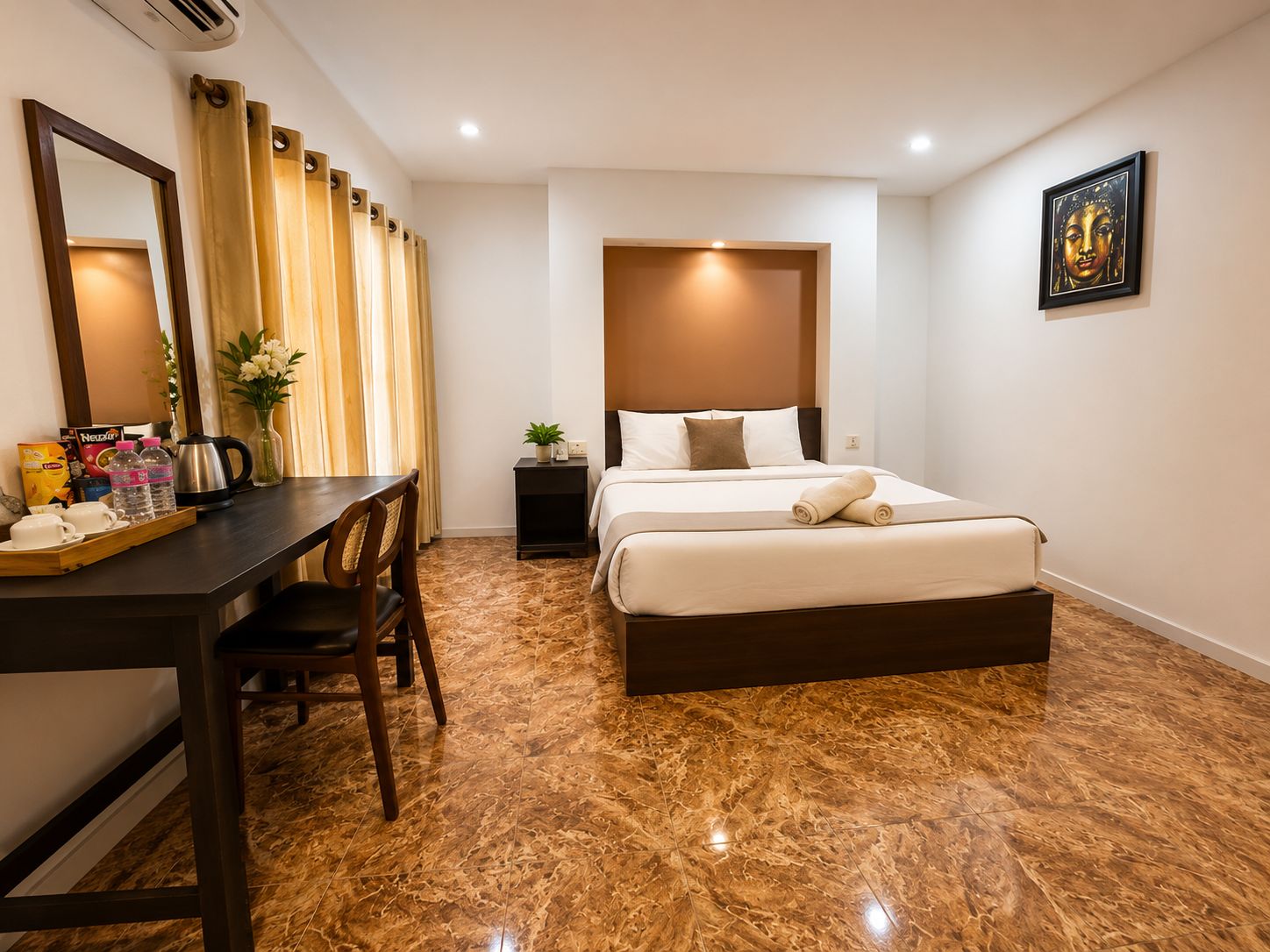 A hotel room with a bed, a desk with a chair, a coffee maker, and a plant.