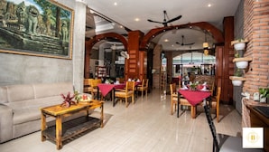 Un restaurante con mesas y sillas de madera, un sofá y un mural en la pared.