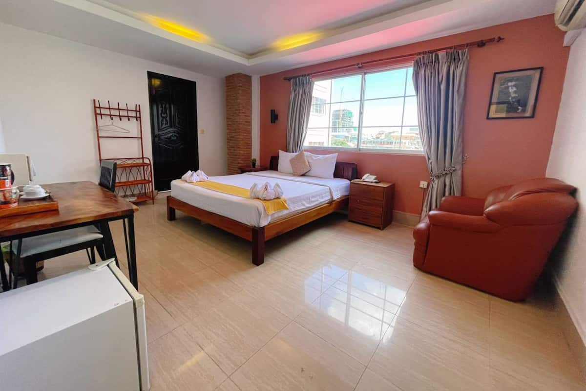 A hotel room with a bed, a desk, a chair, and a window with curtains.
