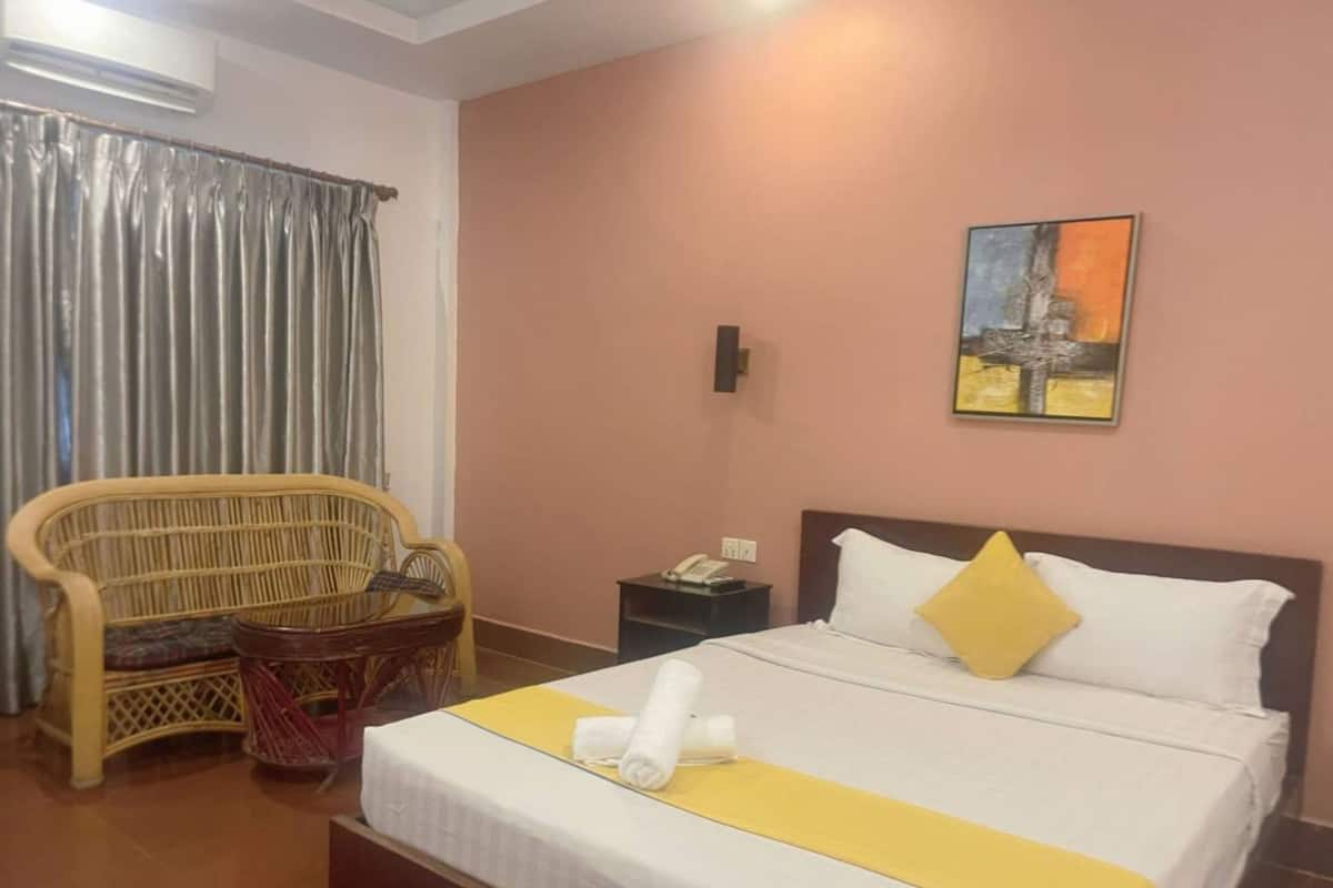 A hotel room with a bed, a nightstand, a chair, and a painting on the wall.