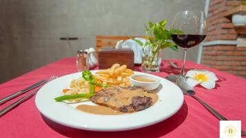 Ein Teller mit Steak, Gemüse und Pommes auf einer roten Tischdecke.