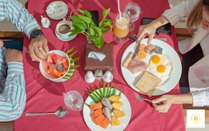 A breakfast setting with plates of food, a plant, and a bottle of juice on a table. - Best Central Point Hotel (Phnom Penh)