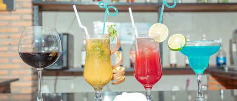 Four different cocktails on a bar counter with a brick wall and shelves in the background.