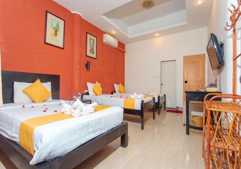 Habitación de hotel con dos camas, un televisor y una silla de madera.
