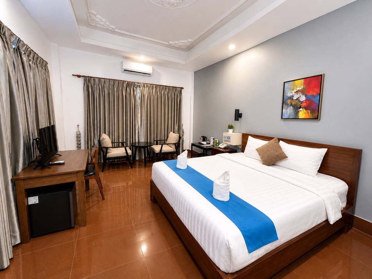 A hotel room with a bed, desk, chair, and a small table.