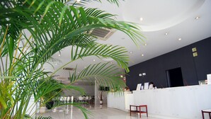 Um hall de hotel moderno com balcão de recepção, área de estar e plantas em vasos.