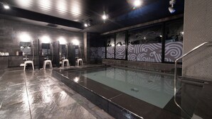 Uma área interna de piscina moderna, com vários espelhos, uma piscina central e um design de parede estampado.