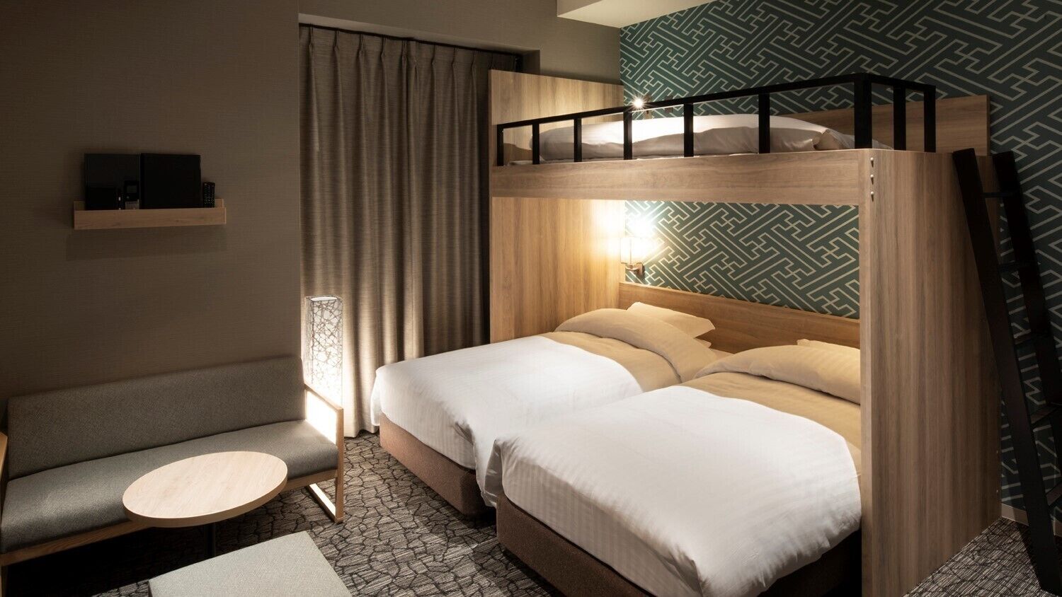 A room with a bunk bed, a sofa, a small round table, and a lamp.