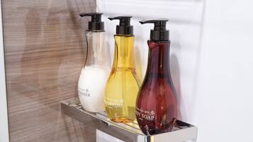 A display of three bottles of shampoo, body wash, and soap on a metallic shelf.