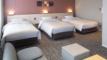 A hotel room with three beds, a sofa, and a small table.