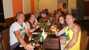 A group of people seated around a table in a dining area with a clock on the wall. - Luxio Hotel Sorong (Sorong)