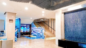 Un hall d’hôtel moderne, décoré sur le thème de la marine, avec une maquette de navire et un escalier doté de rampes en verre.