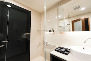 Enjoy a serene bathroom experience with a glass-enclosed shower and a large, minimalist sink.
