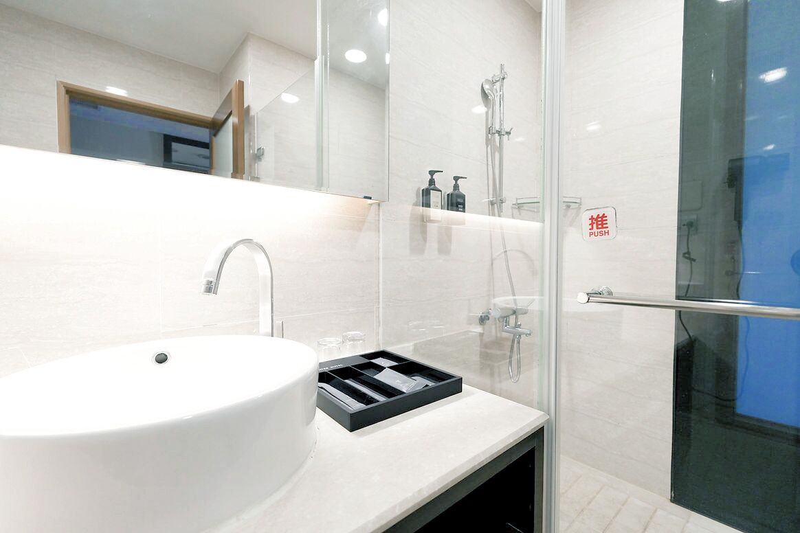 Un baño moderno con un lavamanos blanco, una cabina de ducha de vidrio y un espejo.