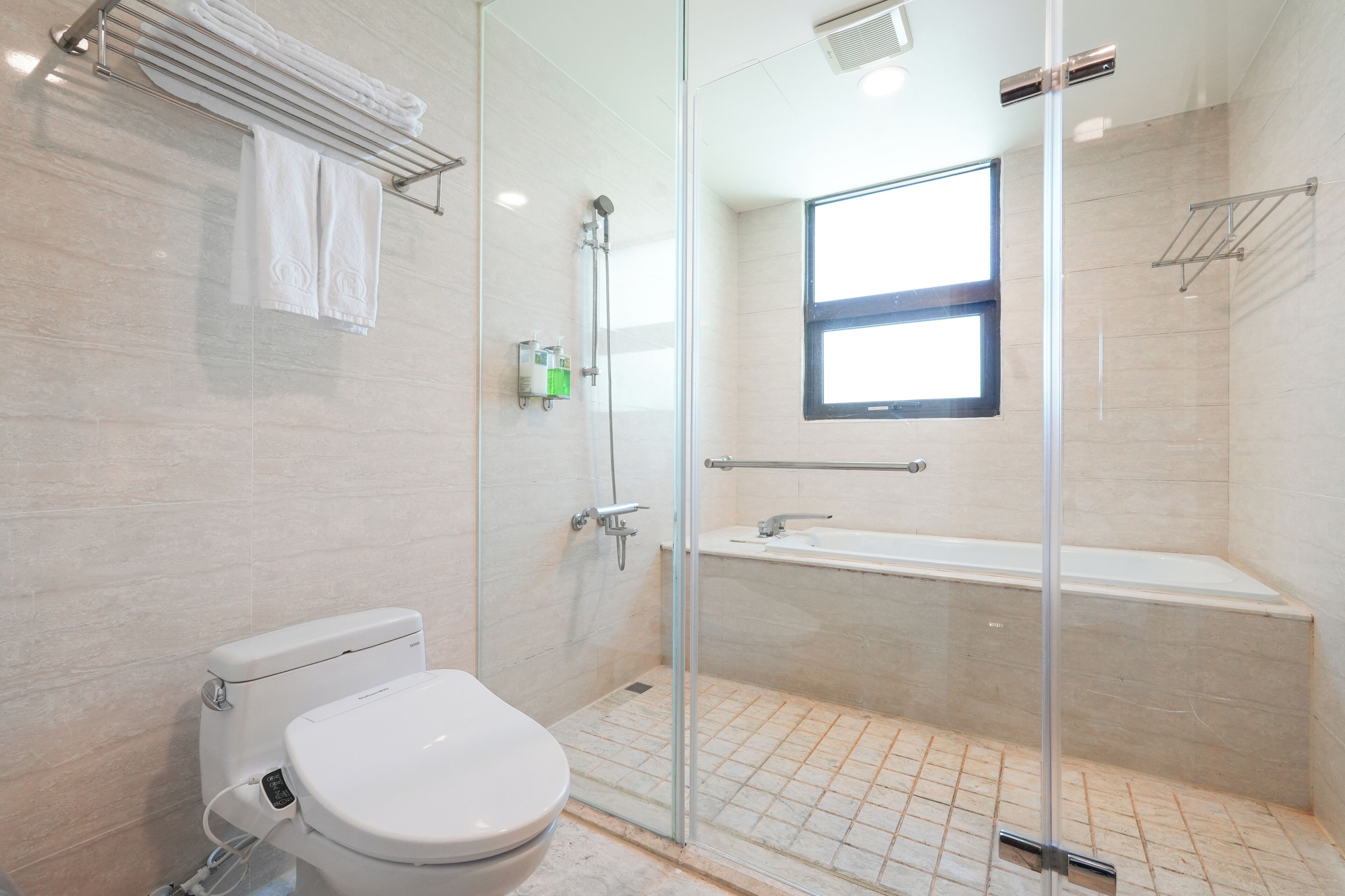 A modern bathroom with a toilet, glass shower enclosure, and a bathtub.