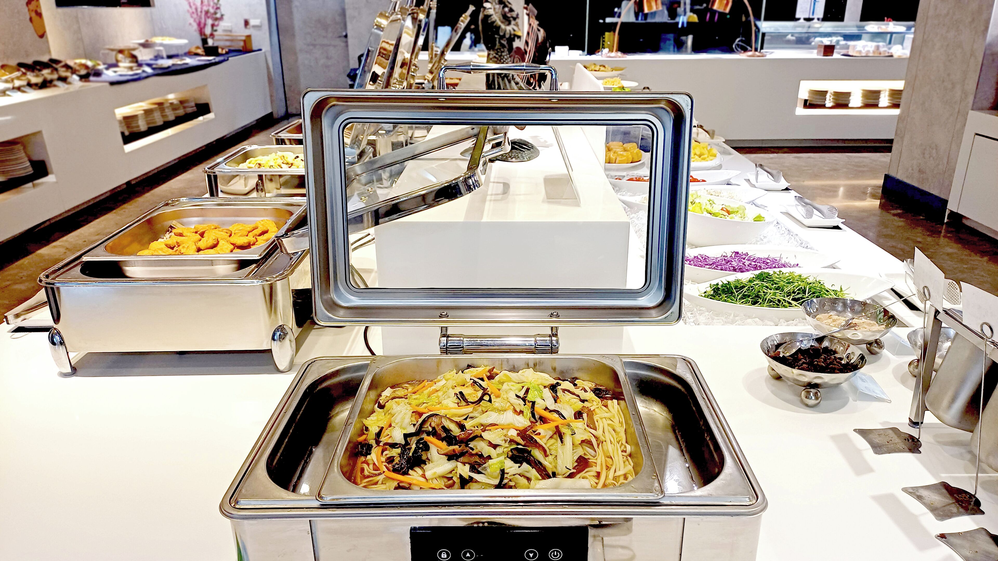 A buffet setup with various food items and utensils.