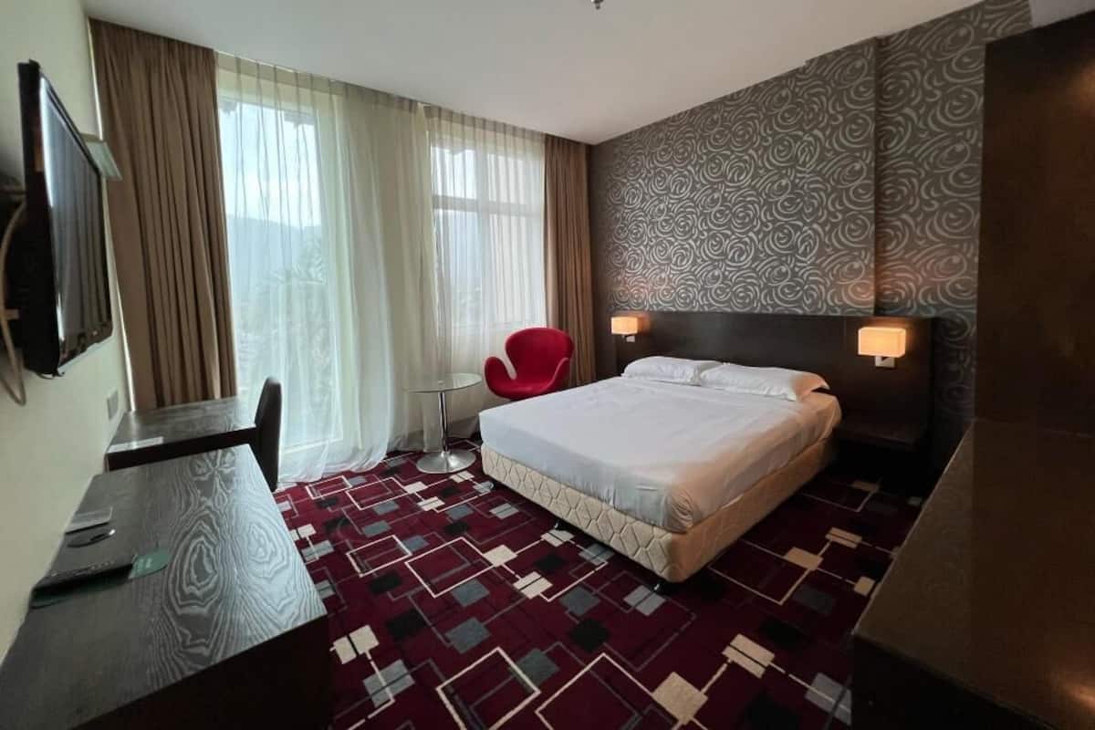 A hotel room with a bed, a desk, a chair, and a TV.