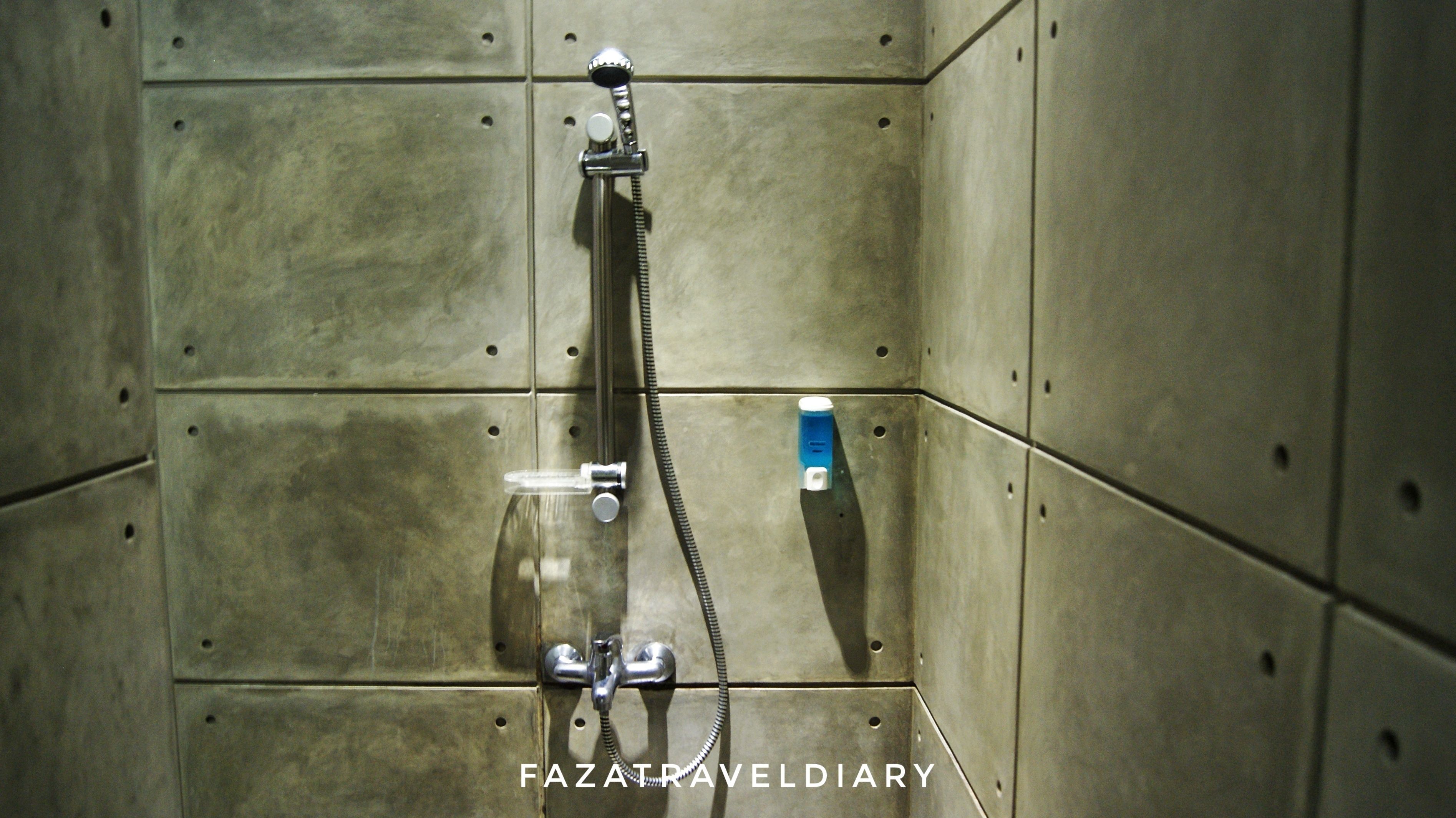 Une douche équipée d’un pommeau de douche et d’un robinet à main.