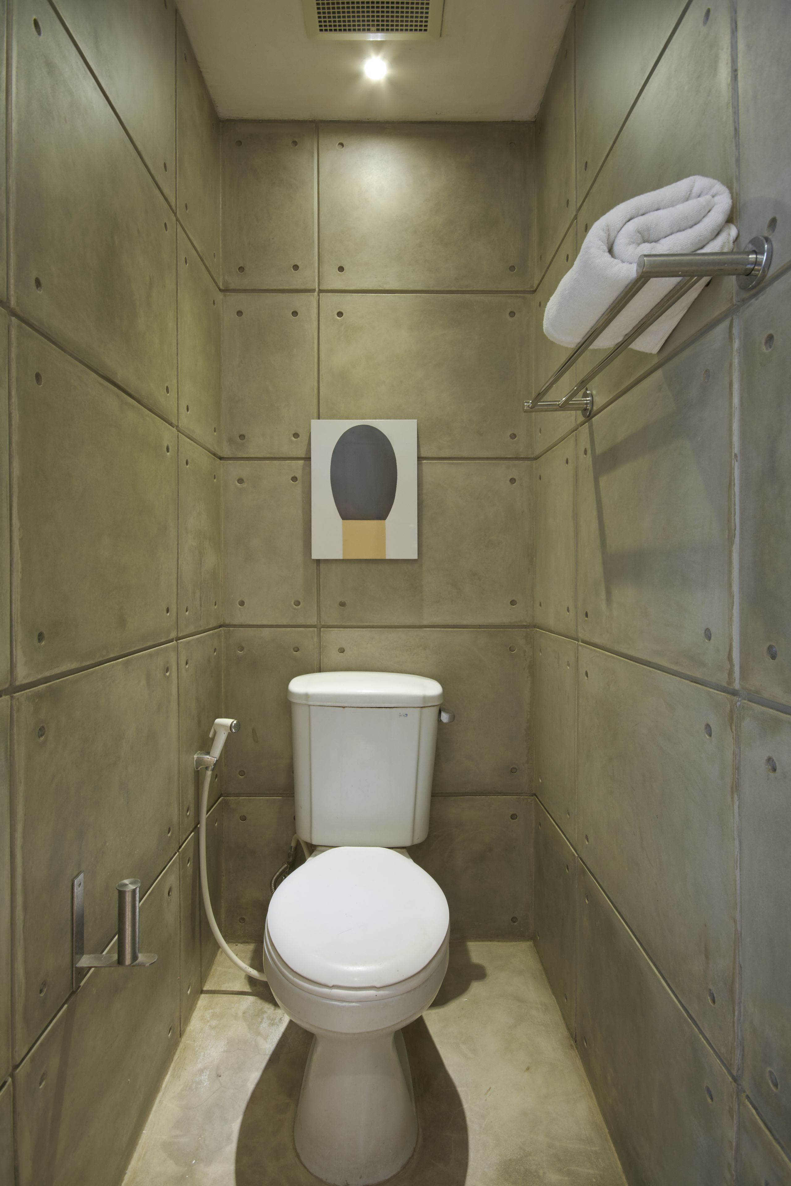 Een compacte, moderne badkamer met toilet, een handdoekhouder en een kunstwerk aan de muur.