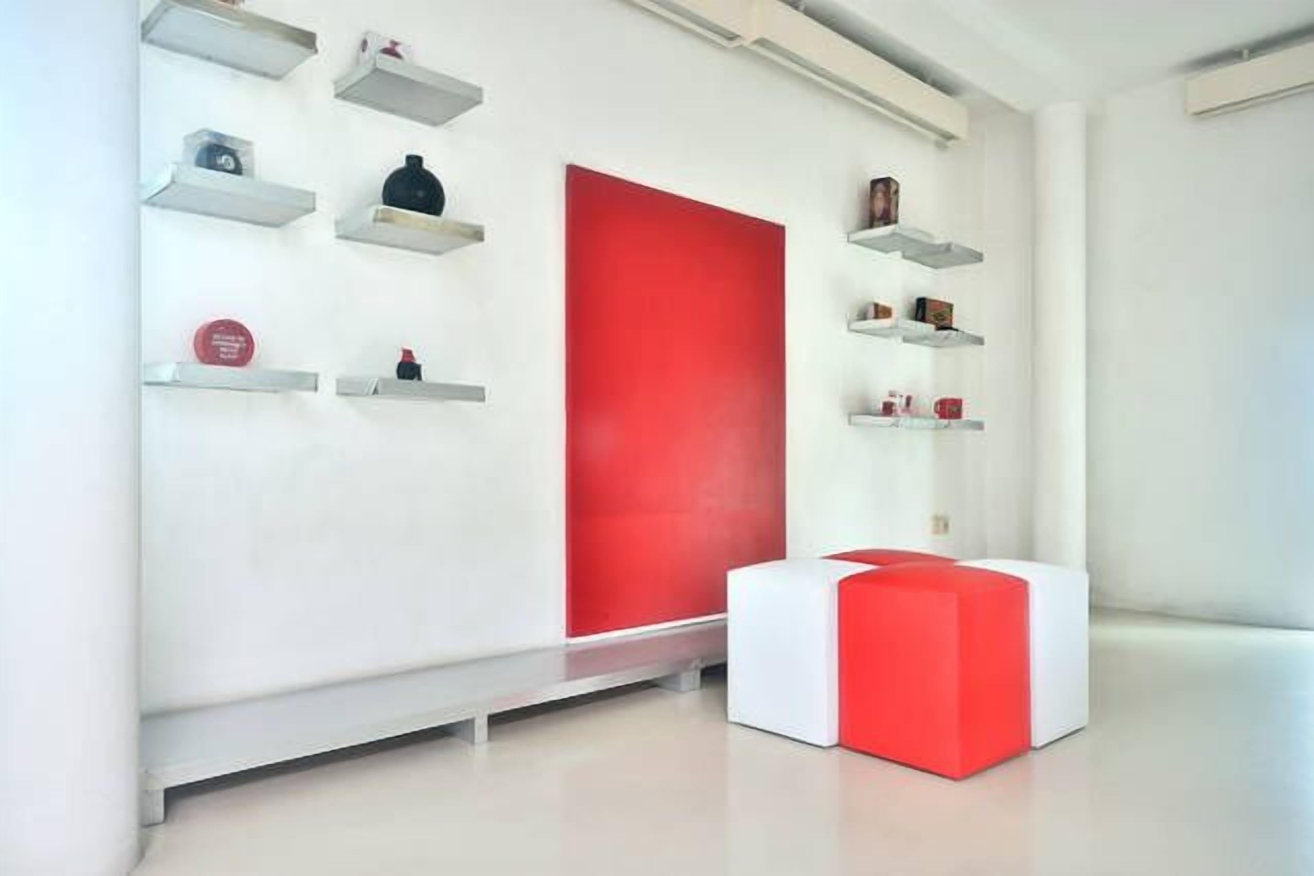 A modern interior with white walls, red accents, and minimalist shelving.