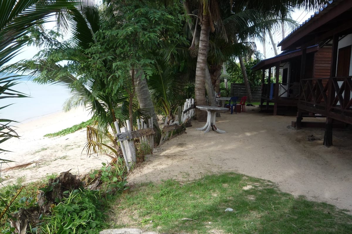 A beachside area with a wooden deck, a table, and chairs.