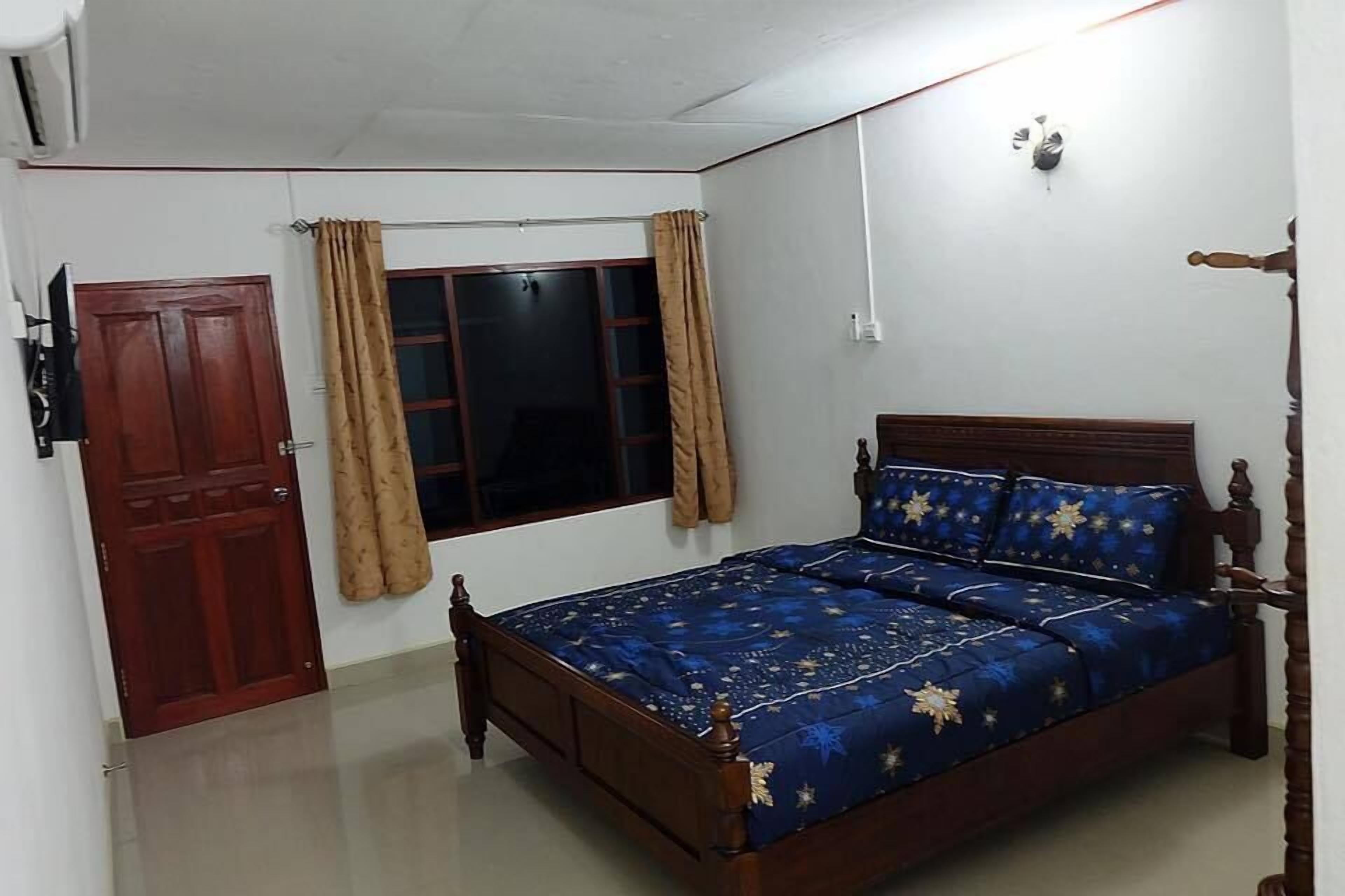 A bedroom with a wooden bed, a window with curtains, a door, and a ceiling fan.