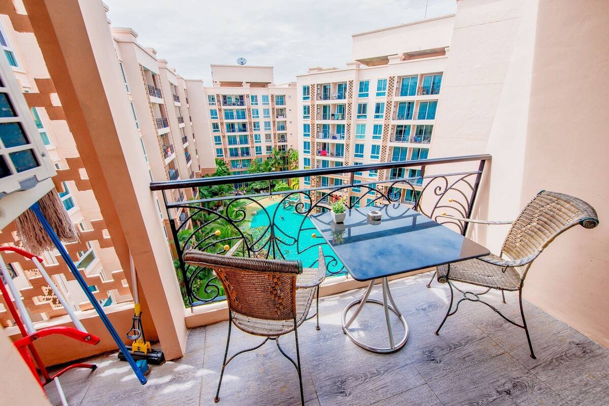 A balcony with a table and chairs, a view of neighboring buildings, and a railing.