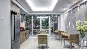 A modern kitchen with a built-in refrigerator and a dining area with wicker chairs and glass tables.
