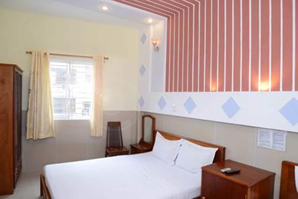 A hotel room with a bed, bedside table, and a mirror.