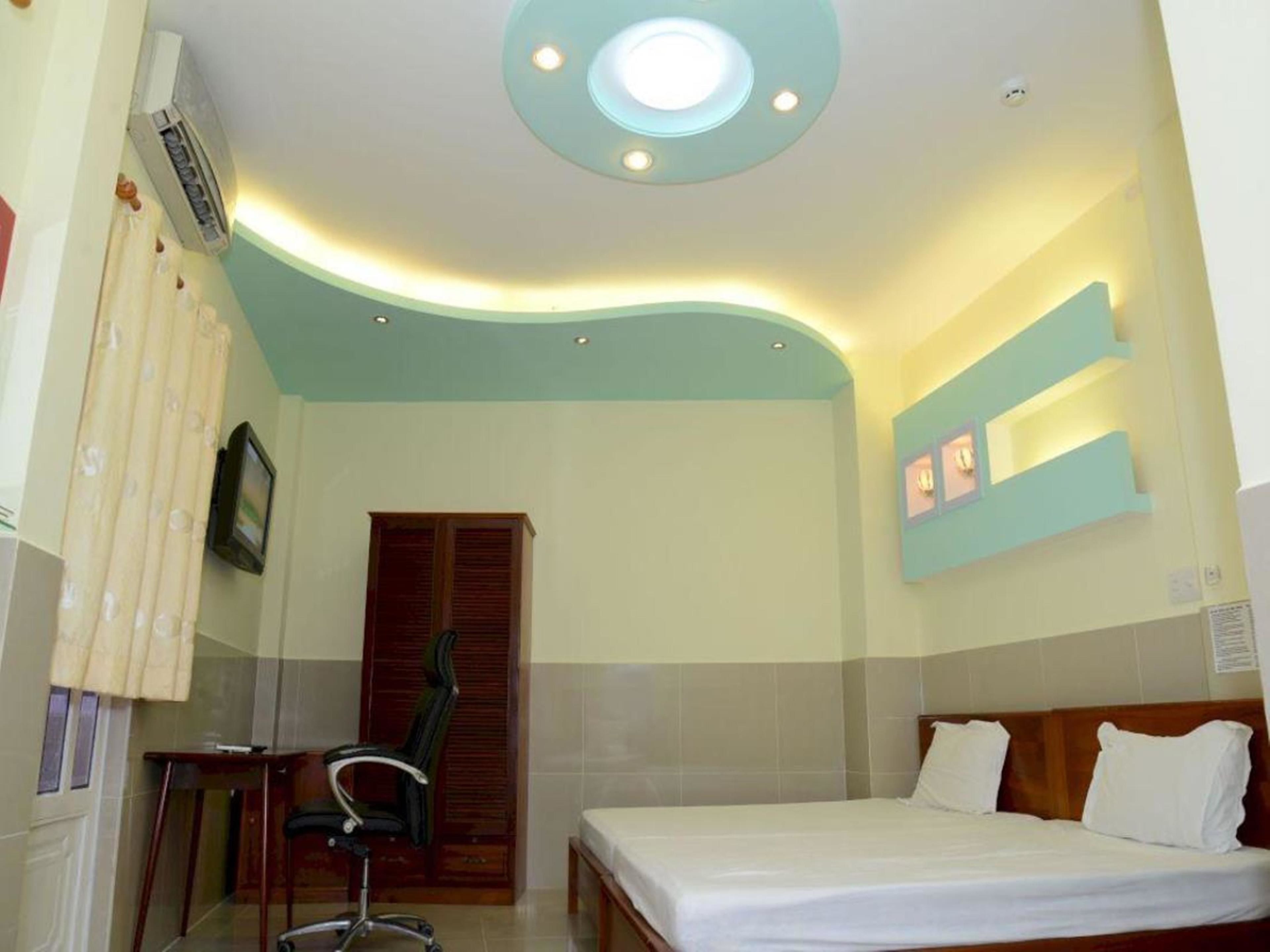 A hotel room with a curved ceiling, a bed, a desk with a chair, and a wall-mounted TV.
