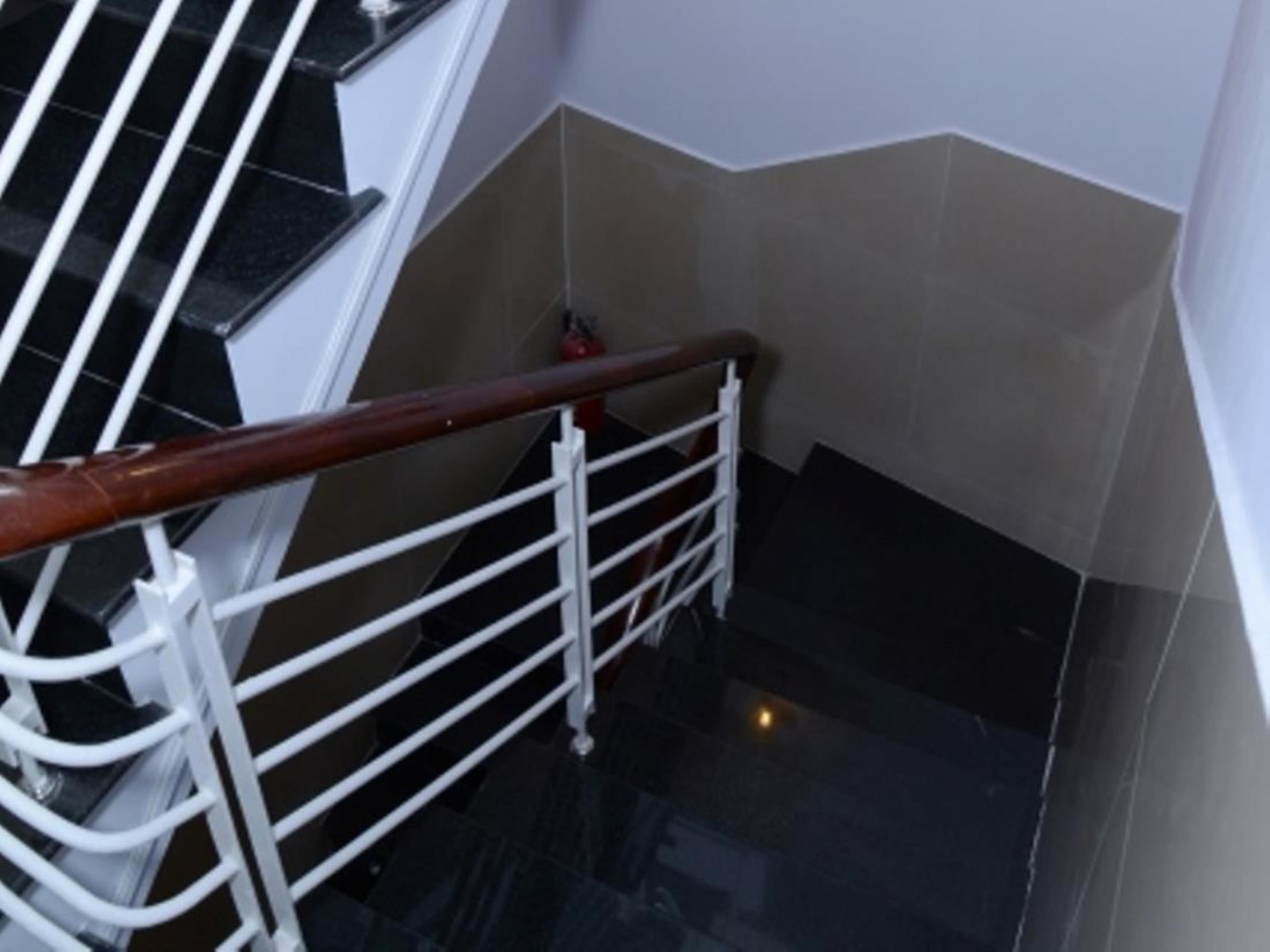 Uma escada com corrimão de madeira e grades de metal branco.