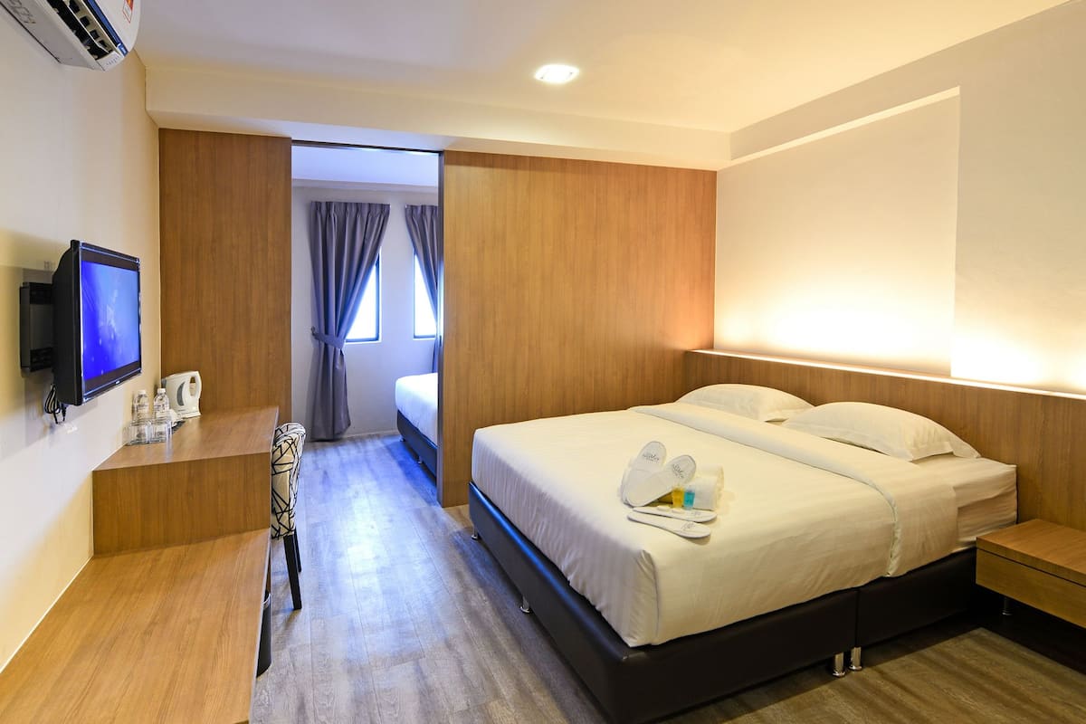 A hotel room with a bed, bedside table, TV, and a desk with a chair.