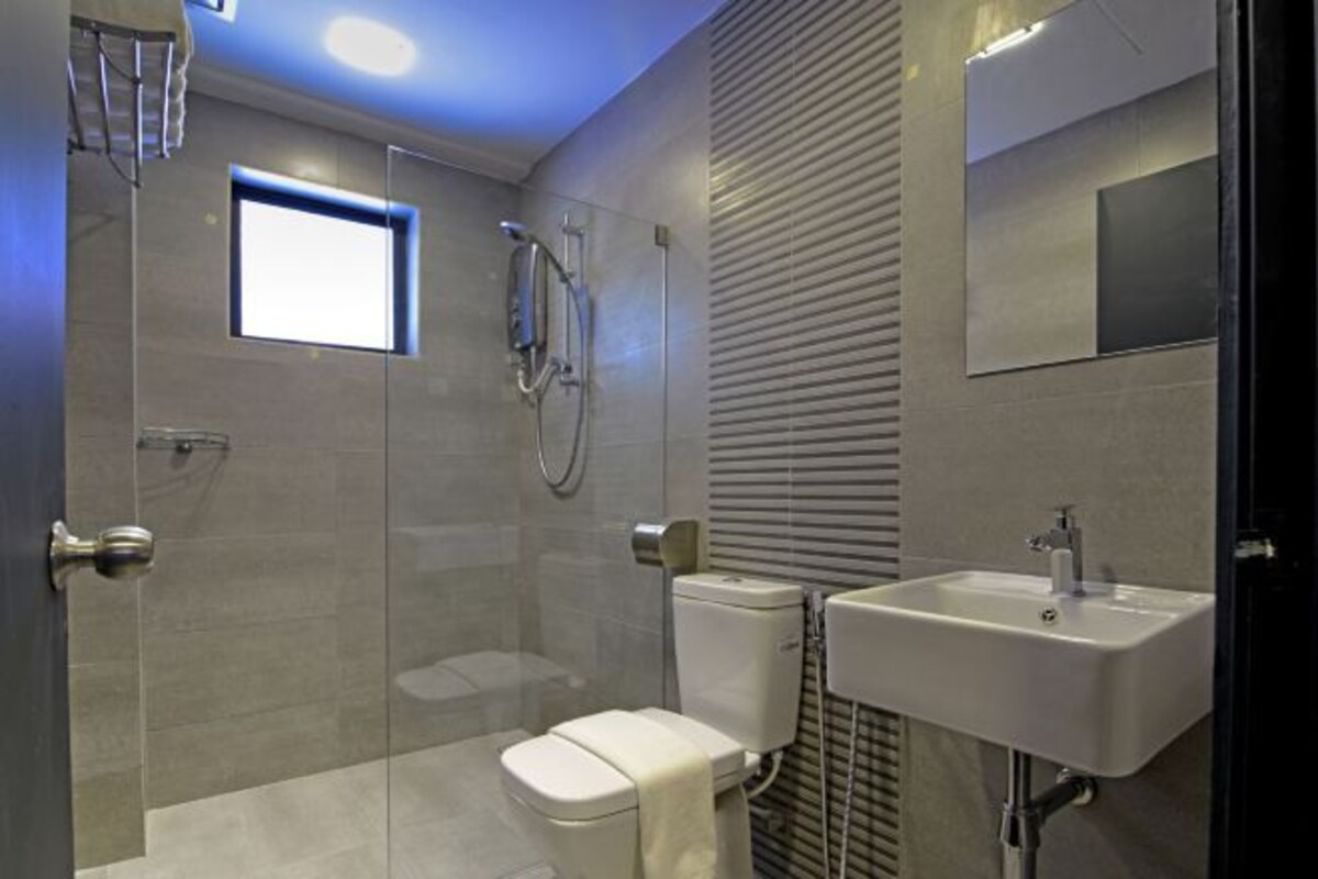 A modern bathroom with a glass shower enclosure, a toilet, and a sink with a mirror.