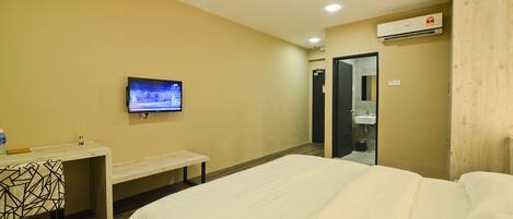 Una habitación de hotel con cama, escritorio, televisor y puerta al baño.