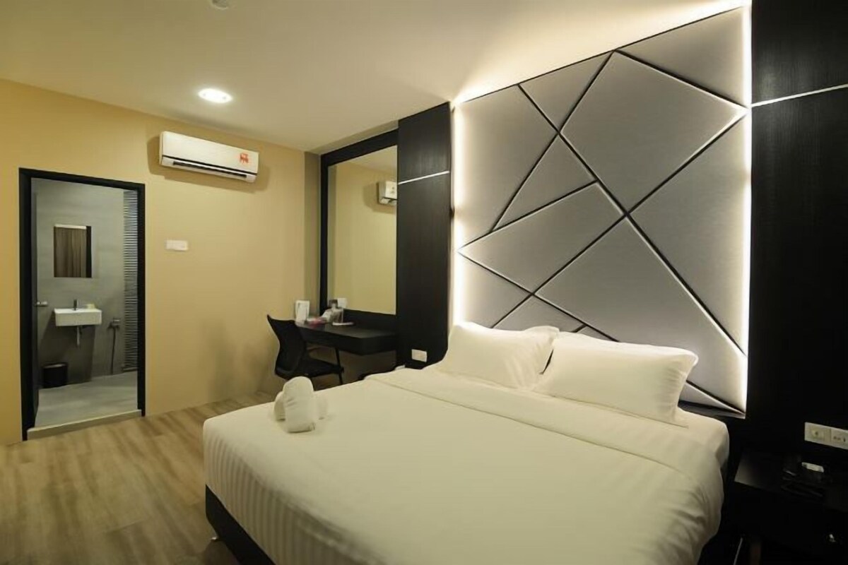Een moderne hotelkamer met een groot bed, een bureau en een spiegel.