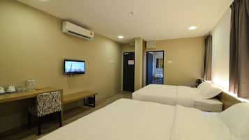 Una habitación de hotel con dos camas, un escritorio con una silla, un televisor y un equipo de aire acondicionado.