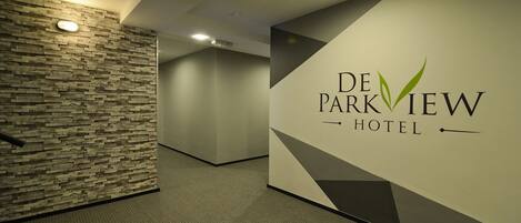 A hallway with a stone wall and a sign for De Parkview Hotel.