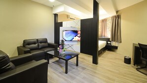 A modern hotel room with a sofa, a coffee table with flowers, a TV, a bed, and a desk. - De ParkView Hotel (Ipoh)