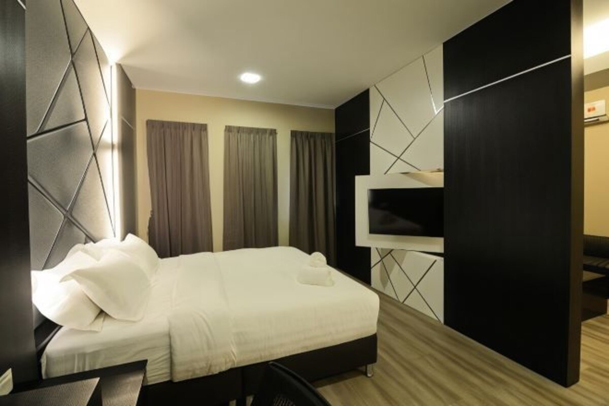 A modern hotel room with a large bed, a desk, and a built-in TV.