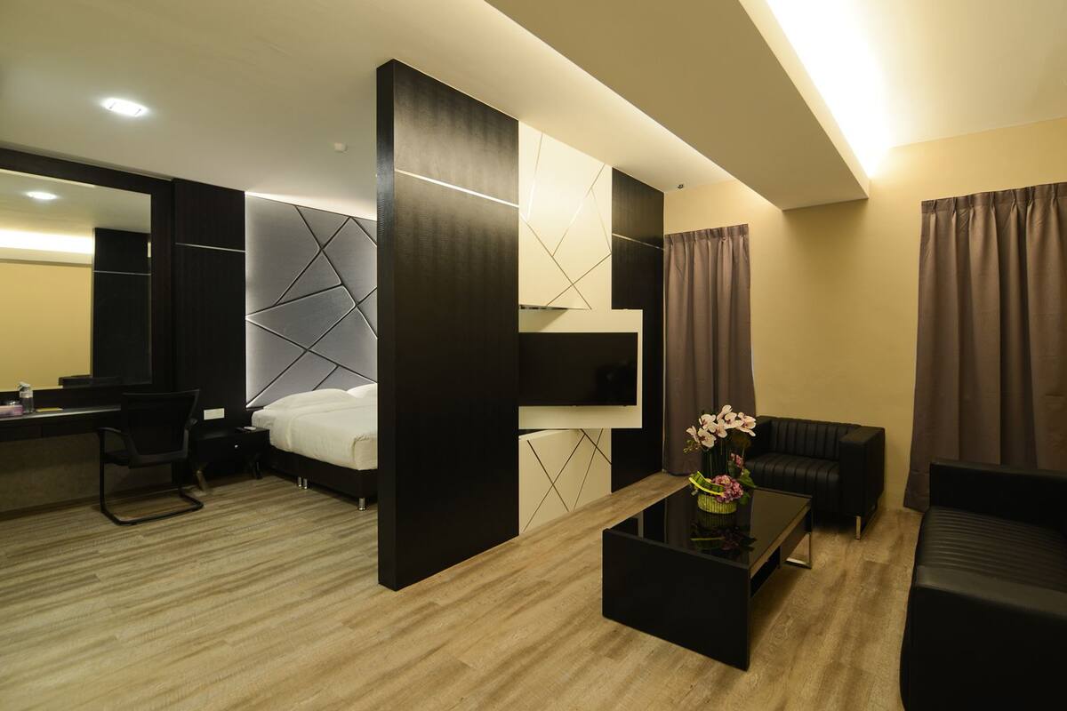 A modern hotel room with a bed, a desk, a TV, a sofa, and a coffee table.