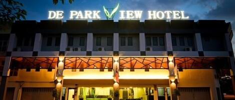 The exterior of De Park View Hotel with a prominent illuminated sign, a modern architectural design, and a well-lit entrance.