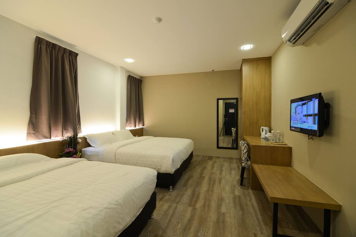 A hotel room with two beds, a TV, a desk, and a mirror.