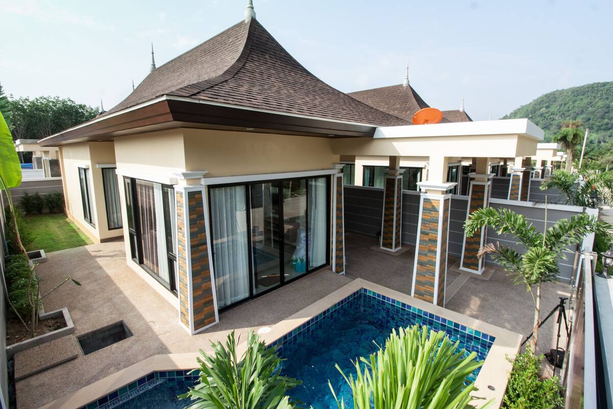 Une maison moderne dotée d’une piscine, de grandes portes vitrées et d’un toit recouvert de tuiles.