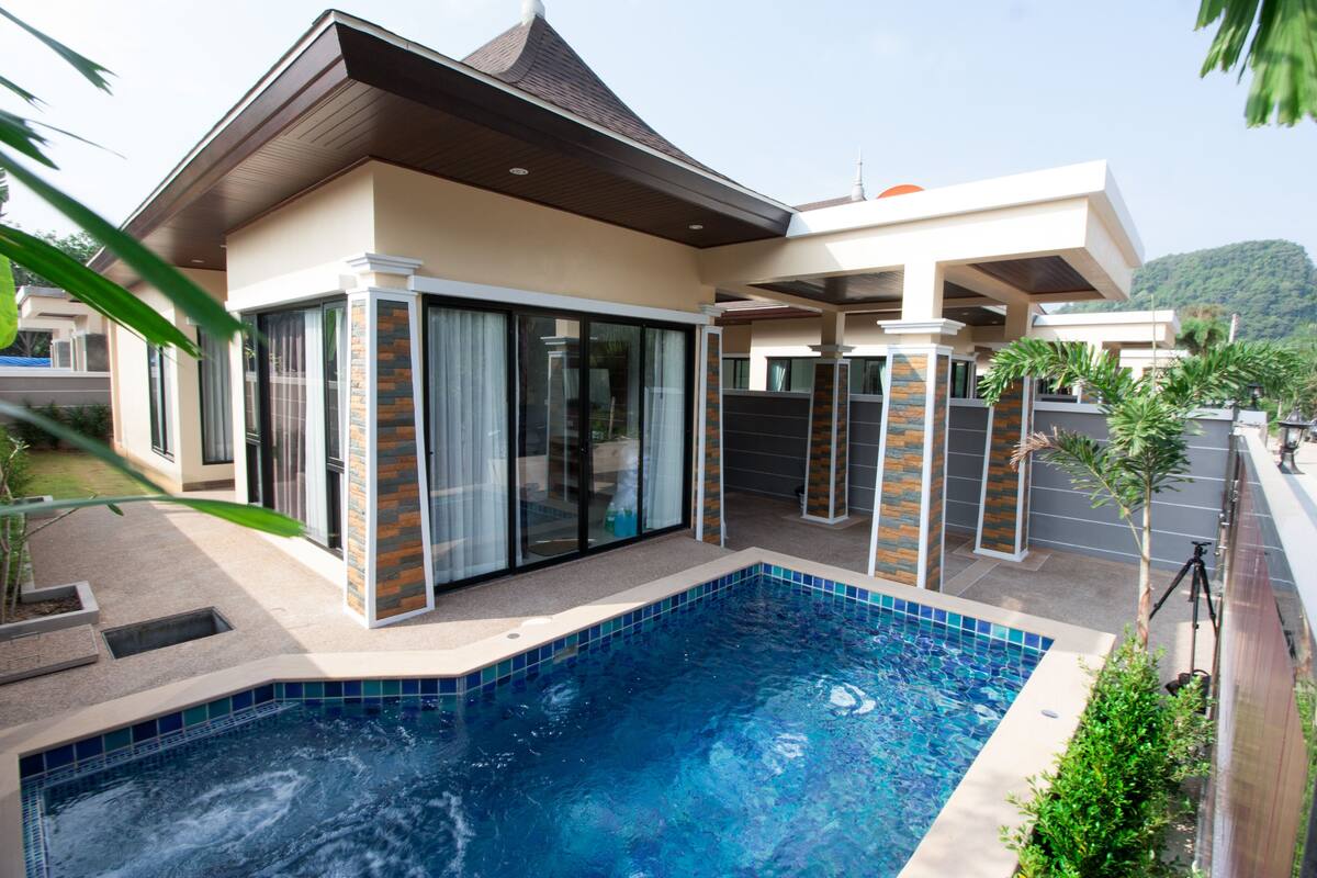 Une maison moderne dotée d’une piscine, de grandes portes vitrées et d’un patio couvert.