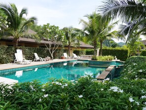 Una piscina rodeada de palmeras y sillones de descanso.