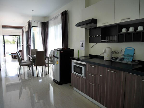Una cocina moderna con refrigerador, microondas y cafetera. Cuenta con un comedor con sillas y una mesa.