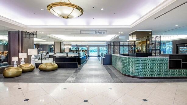 Um lobby espaçoso com balcão de recepção, área de estar e vista para o exterior.