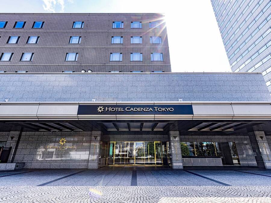 The entrance of Hotel Cadena Tokyo with a modern design, featuring a prominent entrance with glass doors and a clear view of the surrounding urban environment.