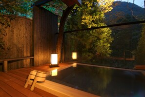 A wooden deck with a hot tub and two lanterns, surrounded by trees and a mountain view. - Yamanaka Onsen Ohanami Kyubei (Kaga)