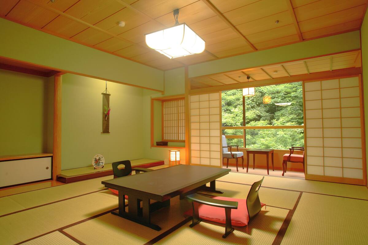 Une pièce de style japonais traditionnel, avec un sol recouvert de tatamis, une table basse et des portes coulissantes.